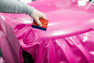 Car wrapping specialist putting vinyl foil or film on car. Selective focus.