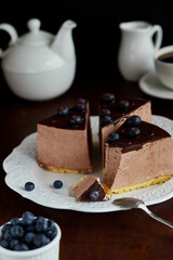 Bird's milk chocolate mousse cake garnished with blueberries on a dark background