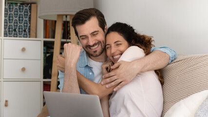 Excited young couple feel euphoric winning online lottery on laptop. Happy overjoyed millennial man...