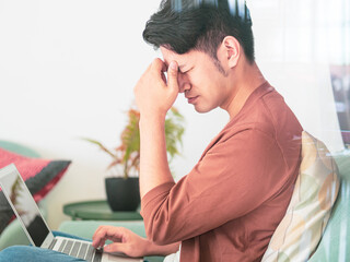 Young Asian man wearing casual clothes and having a headache