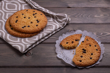 large oatmeal cookies with chocolate chips on a napkin on a wooden table