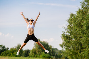 Fototapeta na wymiar Young slim fit woman jump against the sky background