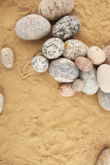 Fototapeta na wymiar Sand background with sea smooth oval pebbles. Heap of stacked round pebbles on beach with copy space.
