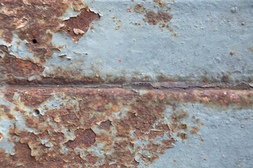 Rust has appeared on the blue painted metal wall.