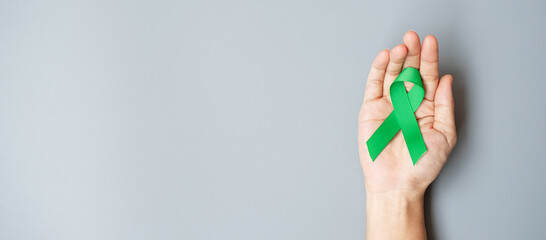Man holding green Ribbon for supporting people living and illness. Liver, Gallbladders bile duct, kidney Cancer and Lymphoma Awareness month concept