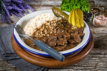 Beef stew served with barley and pickled cucumber.