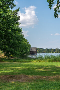Der Haussee mit B&auml;umen und Pfahlbau H&uuml;tte