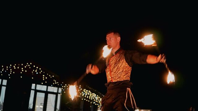 The guy waves two burning staffs in front of him. Beautiful slow motion footage