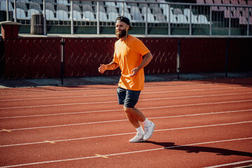 Healthy lifestyle. Handsome male athlete with long beard running while listening to music using...