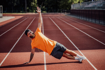 Healthy lifestyle. Handsome caucasian male athlete with long beard doing strength exercises in the stadium for cardio workout