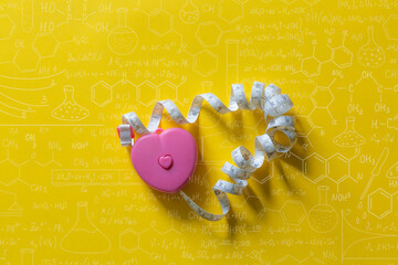 Heart-shaped tape measure on a yellow background,Hand drawn science formulas on chalkboard for background.