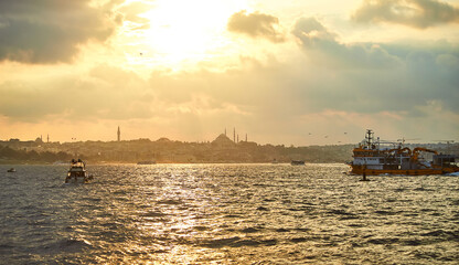 Sunset over Istanbul with a view of the Suleymaniye  Mosque and City line ferry and boats. Traditional arabic town with silhouettes of minarets on sunset, ancient landmarks of architecture in Turkey.