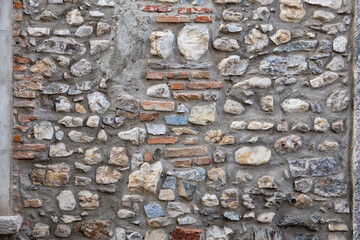old irregular stone wall with red bricks