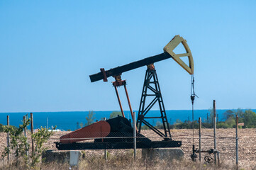 Opetating petrol oil well pump jack in summer sunny day