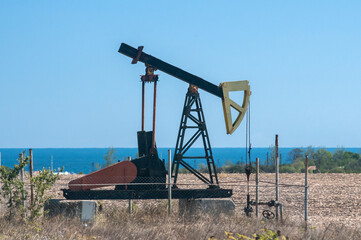 Fototapeta na wymiar Opetating petrol oil well pump jack in summer sunny day