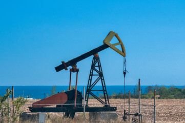 Fototapeta na wymiar Opetating petrol oil well pump jack in summer sunny day