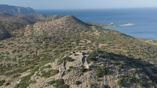 Aerial drone view of a dry, yellow landscape along the Greek coastline in Summer (Kolokytha, Elounda, Crete)