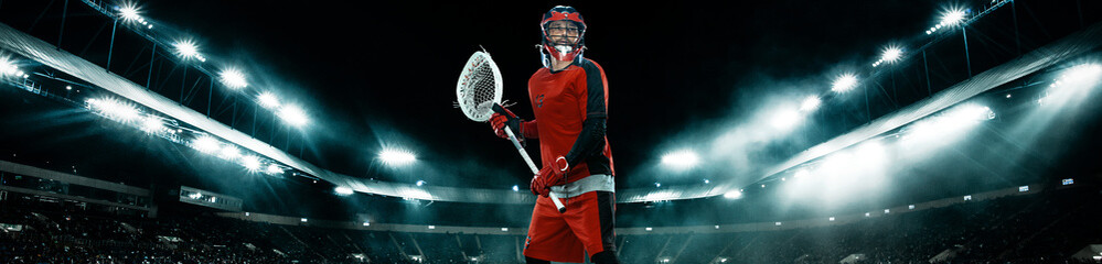 Lacrosse Player, athlete sportsman in red helmet on stadium background with lights. Sport and motivation wallpaper. Wide banner.