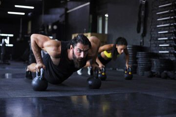 Sporty man and woman doing push-up in a gym.