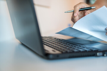 Businessman hands working in laptop computer with paper files searching information business report...