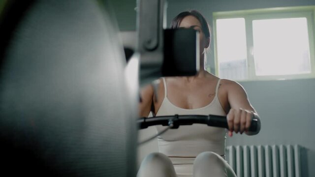 Athletic Woman Has Workout on Rowing Machine .