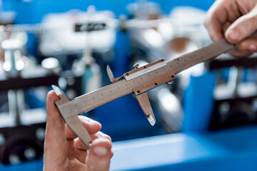 Male hands hold vernier caliper and measure steel collar.