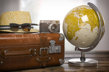 Tourism and travel concept. Globe and vintage suitcase with summer hat, sunglasses photo camera on wooden table.