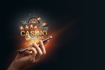 In a man's hand a smartphone with playing cards roulette and chips, black-gold background. Concept...