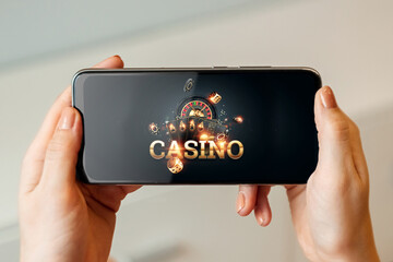 Creative background, online casino, in a man's hand a smartphone with playing cards, roulette and...
