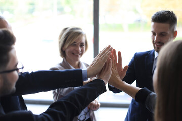 Successful business team giving each other high five standing in the office.