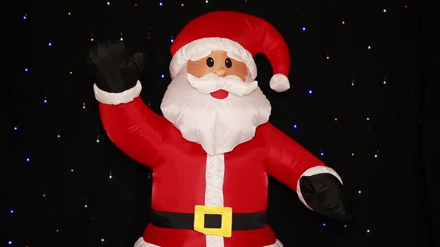 Inflatable growth doll Santa Claus, in a red suit, isolated on a black background with flashing lights. Happy New year celebration happy holiday