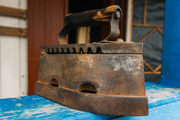 Antique charcoal iron. Vintage iron on wooden blue shelf.Old fashioned ironing tools.Heritage concept.