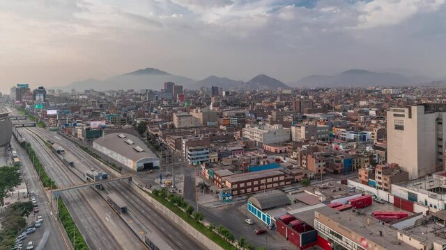 Aerial panoramic view of Via Expresa highway and metropolitan bus with traffic timelapse near National Stadium of Peru. Houses and city skyline with mountains on a background. Lima, Peru