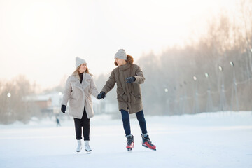 Fototapeta na wymiar Happy young couple in sunny winter nature ice skating