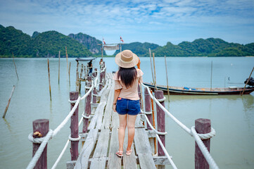 Obraz premium A woman standing on a wooden jetty bridge at Talet bay, Khanom, Nakhon Si Thammarat, Thailand