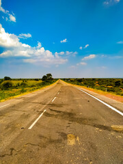 Road of asphalt in Rajasthan India with green trees and blue sky white clouds