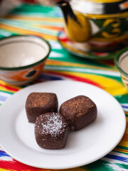  dessert chocolate brownie potatoes in oriental style on a tar with a teapot and a cup for tea.
