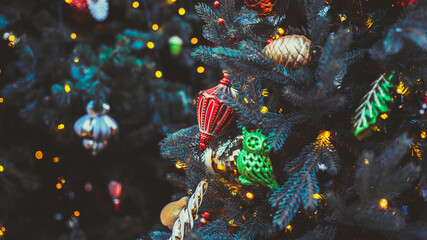 Close up of part of Christmas tree with different christmas toys and garland on street in evening...