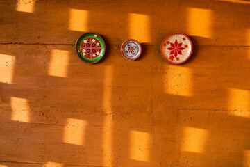 Red terracotta color clay wall with handmade souvenir plates as decoration. Moroccan culture,...