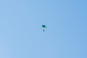 Tandem parachute jump. Silhouette of skydiver flying in blue clear sky. Concepts of extreme sport and adrenaline.