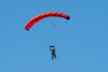 Tandem parachute jump. Silhouette of skydiver flying in blue clear sky. Concepts of extreme sport...