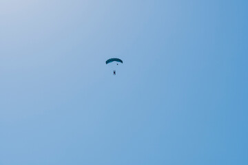 Tandem parachute jump. Silhouette of skydiver flying in blue clear sky. Concepts of extreme sport...