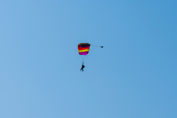 Tandem parachute jump. Silhouette of skydiver flying in blue clear sky. Concepts of extreme sport...