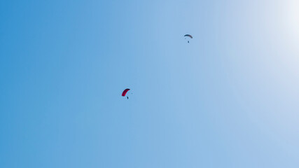 Tandem parachute jump. Silhouette of skydiver flying in blue clear sky. Concepts of extreme sport and adrenaline.