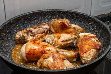 Fresh chicken is fried in a pan on the gas stove.