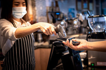 Coffee shop owner, Asian woman Accepting payments from customers With the use of a barcode scanner With the customer's mobile application, to people and new normal concept.