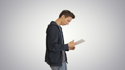 Young man using digital tablet while walking on gradient backgro