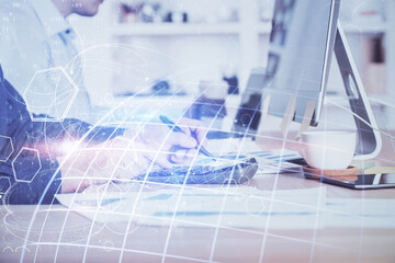 Double exposure of world map hologram with man working on computer on background. Concept of worldwideweb.