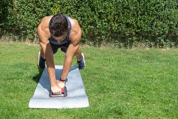young man doing cross-legged push-ups in the garden