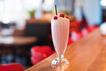 Iced milkshake with raspberry syrup topped with whipped cream